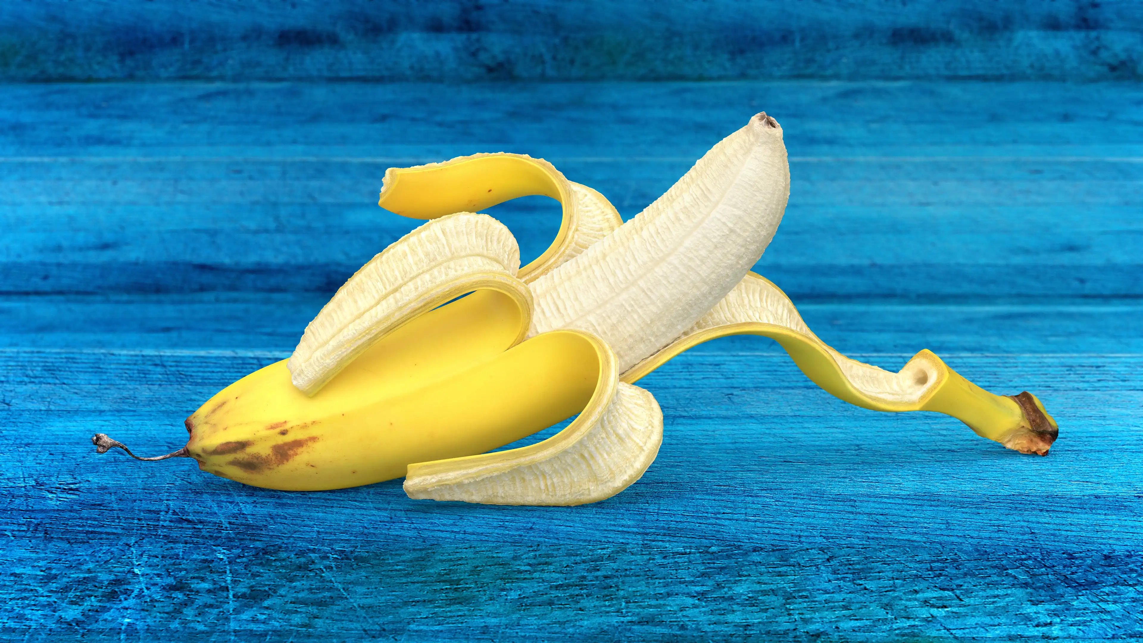 photorealistic scanned banana 3d model with a traditional style of peel opening on blue wooden boards