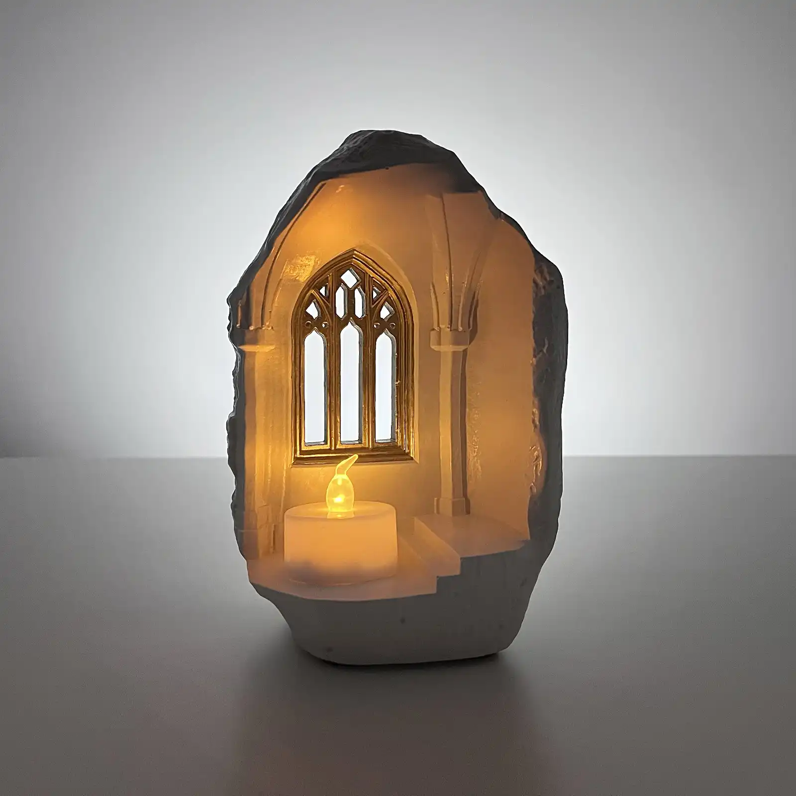 Castle-shaped candle holder glowing warmly in a dark room